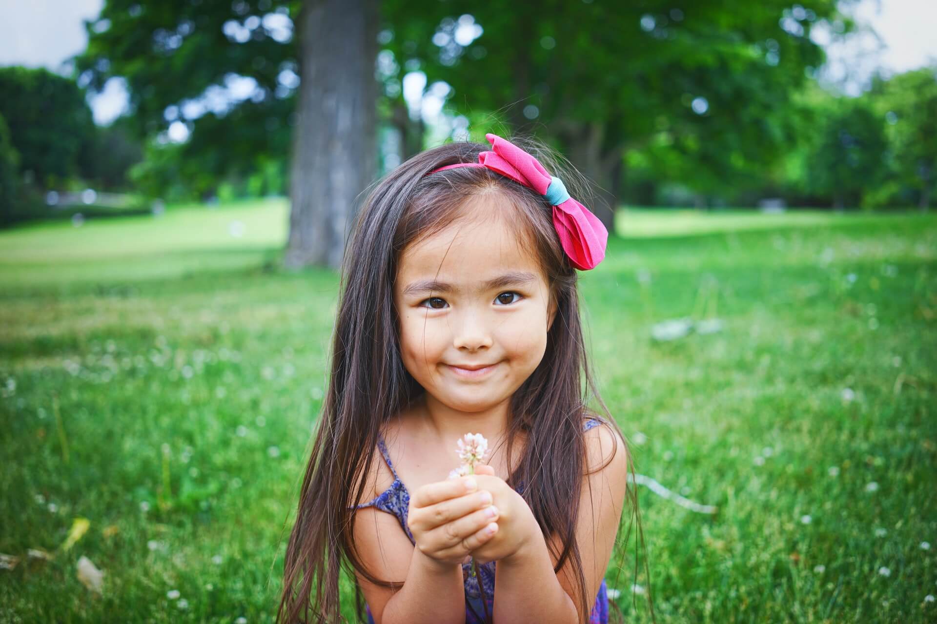 Ett barn med en blomma utomhus.